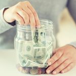 stock image of woman putting money in a jar