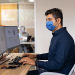 Faculty member wearing mask working at computer