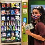 Person using vending machine to buy hand sanitizer and masks